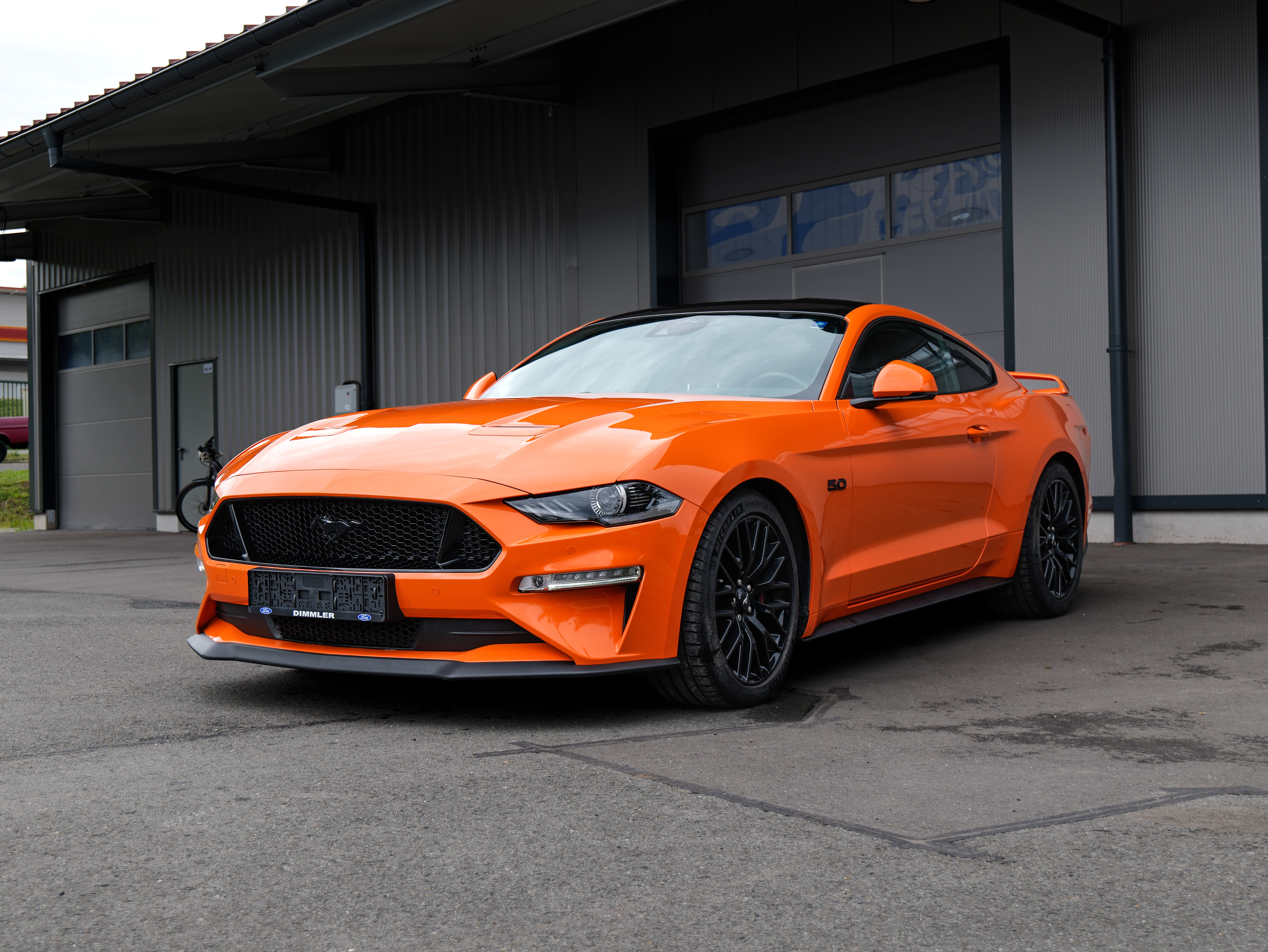 Orangefarbener Ford Mustang vor einer Halle